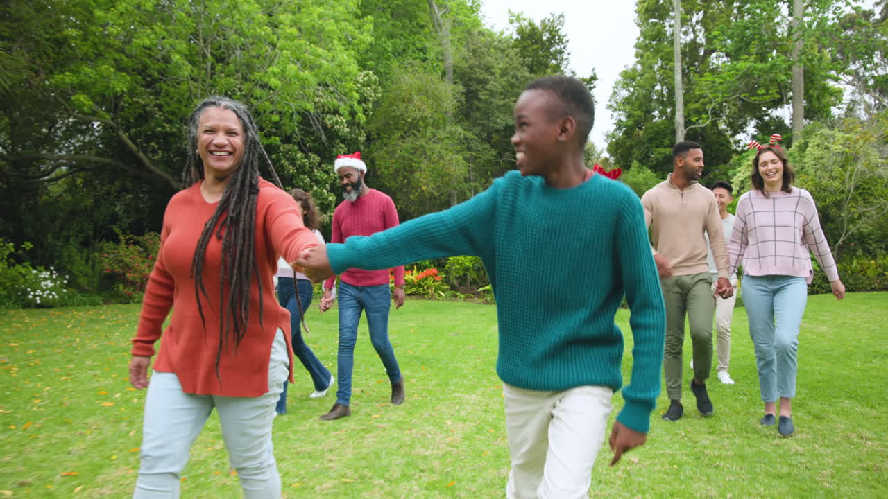 At Christmas, Diverse family enjoying festive outdoor gathering, holding hands and laughing in garde