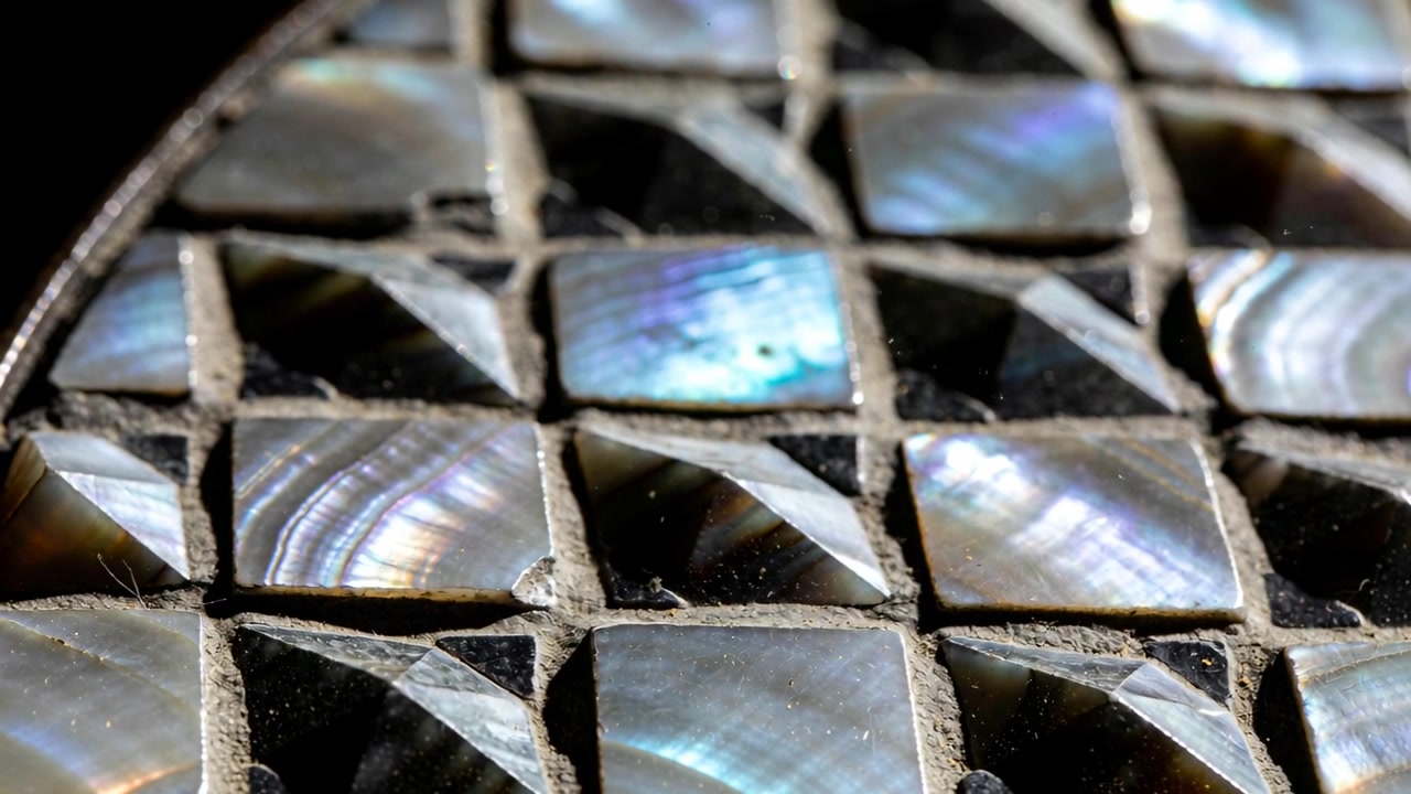 Revealing abalone mosaic in lab as camera shifting focus and light, exposing pearly color and grout