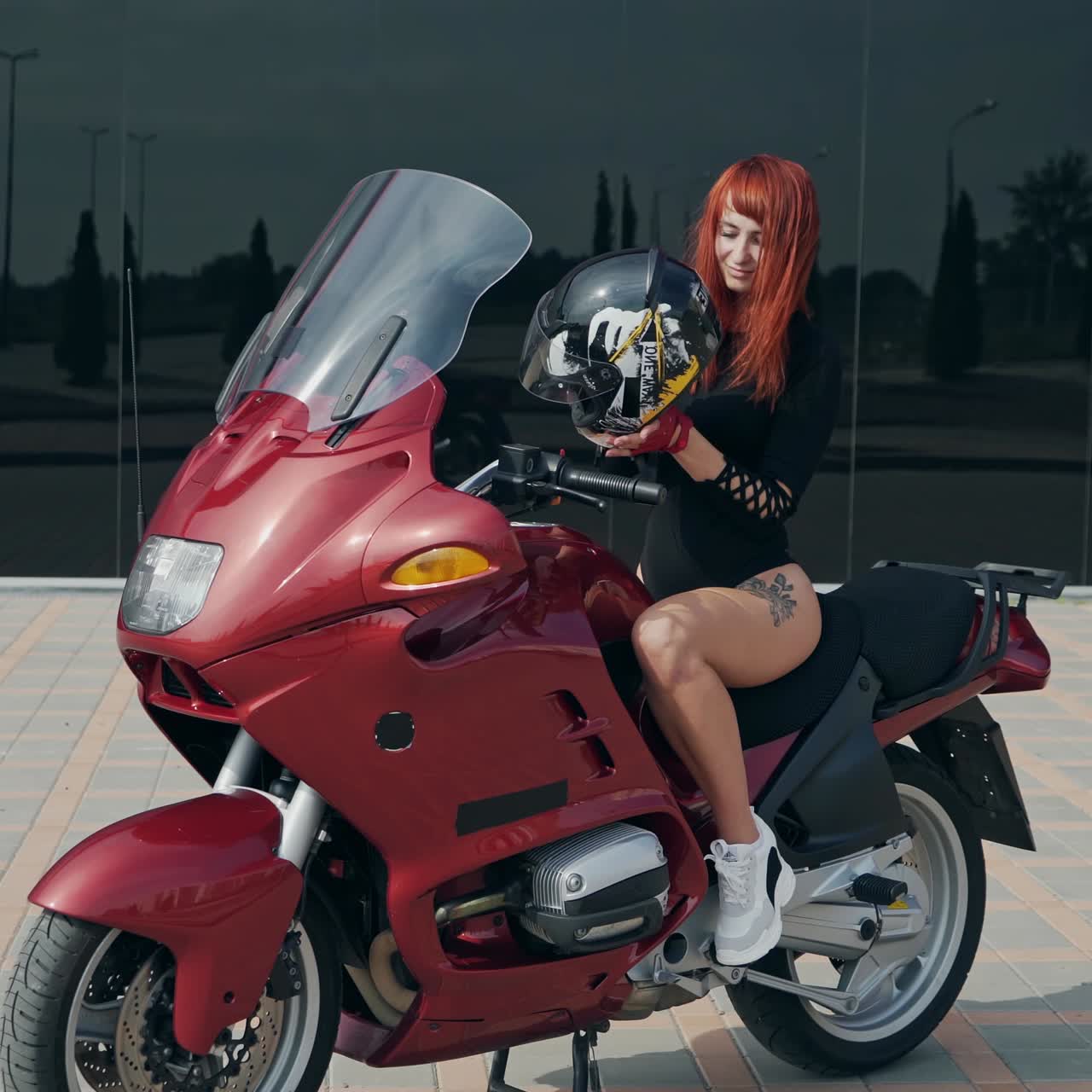 . Young woman on the motorcycle. Happy biker wearing an helmet sitting on her motorbike