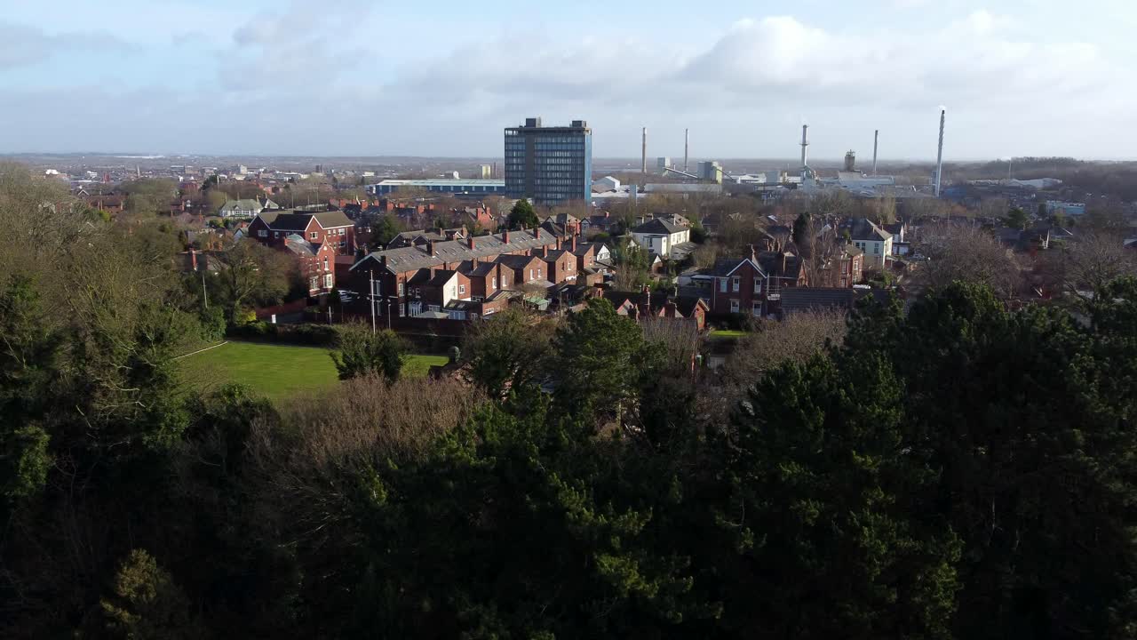 vista aérea sobre los árboles del parque al paisaje urbano industrial con rascacielos azules pilkingtons, merseyside, inglaterra
