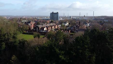 Aerial view over park trees to industrial townscape with Pilkingtons blue skyscraper, Merseyside, England