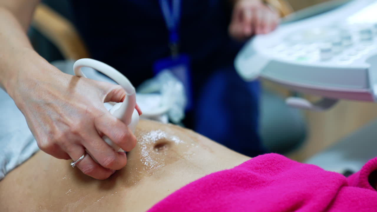Female hand moves the ultrasonic device on the belly of woman. Pregnant lady is checked at ultrasound machine.
