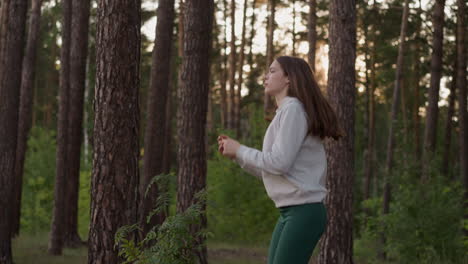 woman jumps exercising in forest with trees. athlete warms up before active jog at sunset. productive fitness activities and improved endurance