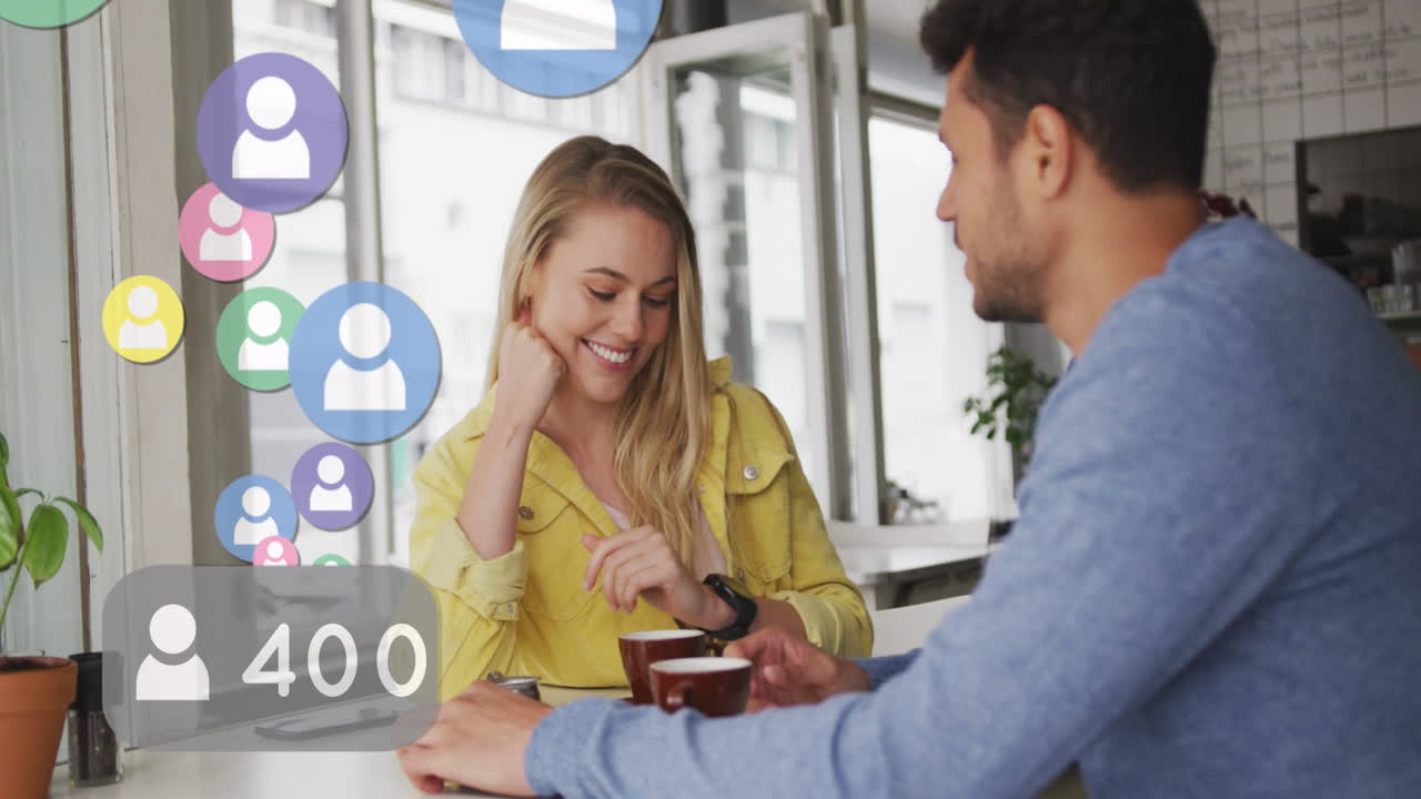 animación de iconos de las redes sociales flotando sobre una feliz pareja caucásica hablando y bebiendo café