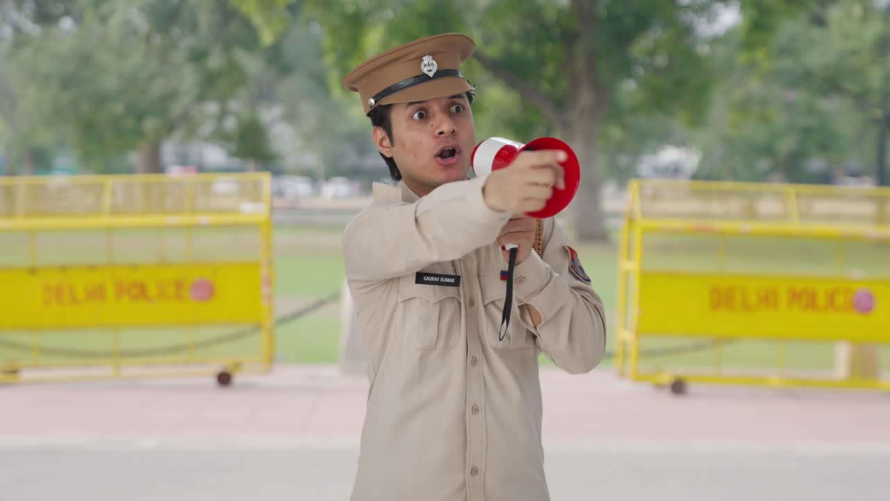 화난 인도 경찰관 이 메가폰 을 사용 하여 까마귀 를 통제 하고 있다