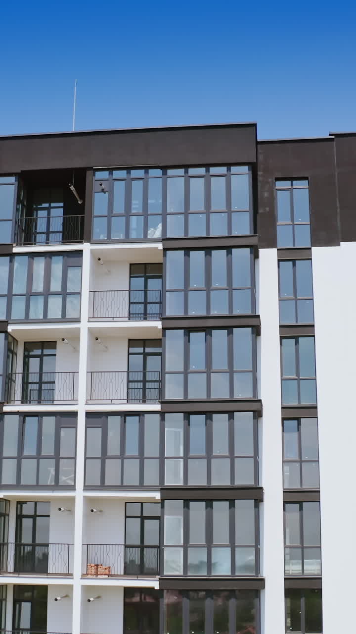 Front view of a beautiful multi-storey building. Modern design of high-raised apartment building with many glass windows and balconies. Aerial view. Vertical video