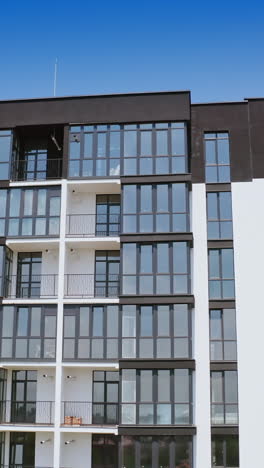front view of a beautiful multi-storey building. modern design of high-raised apartment building with many glass windows and balconies. aerial view. vertical video