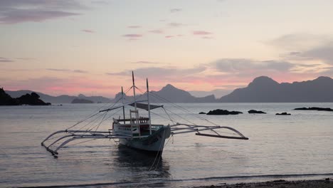 Traditionelles-Philippinisches-Bangka-Boot-Auf-Ruhigem-Wasser-In-Der-Abenddämmerung-Mit-Rosa-Und-Orangefarbenem-Himmel