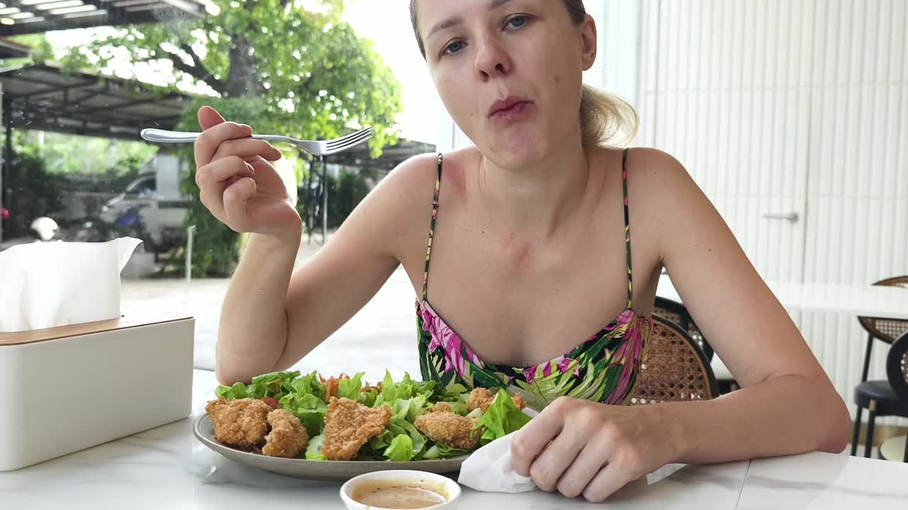mujer comiendo una ensalada de pollo en un café