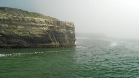 Aerial-Slide-of-Cliffside-Over-Foggy-Ocean-to-Reveal-Flock-of-Pelicans