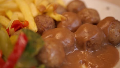 swedish meatballs with gravy, french fries, and vegetables