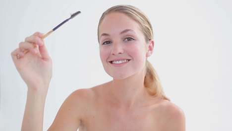 mujer sonriente cepillándose las cejas
