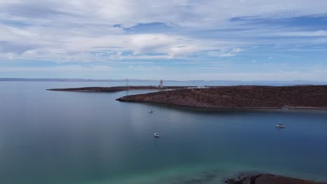 Panorama-Luftaufnahme-Einer-Ausgeprägten-Wüstenlandschaft-Vor-Dem-Ruhigen-Blauen-Meer-Von-Baja-California-Sur-Mexico,-Strand-Playa-El-Tecolote-In-Der-Nähe-Von-La-Paz-Mit-Blick-Auf-Schwimmende-Boote-Im-Meer