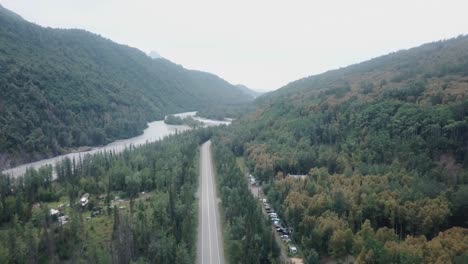 Aerial-view,-drone-flight-along-the-Glenn-Highway-and-the-Matanuska-River-in-the-Chugach-Mountain-Range-of-central-Alaska-on-a-cloudy-summer-day