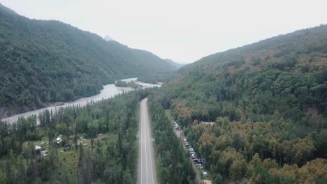 aerial view, drone flight along the glenn highway and the matanuska river in the chugach mountain range of central alaska on a cloudy summer day