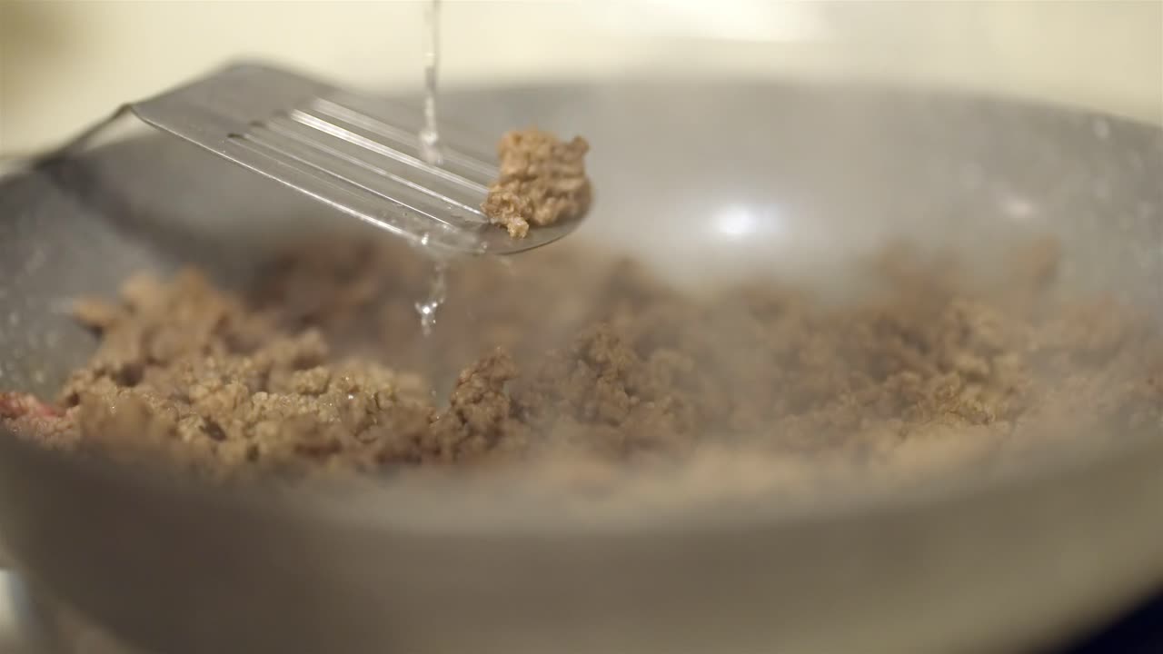 Adding Water to Cooked Ground Beef in a Hot Pan for Taco Filling