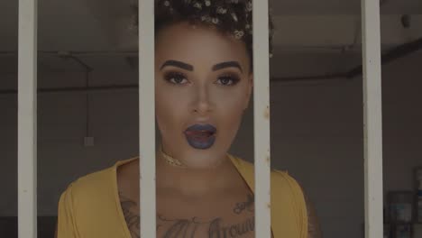 black sexy female moving slowly inside metal bars and looking straight in the camera.