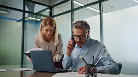 Smiling-businesspeople-collaborating-in-modern-office.-Businessman-talking-phone