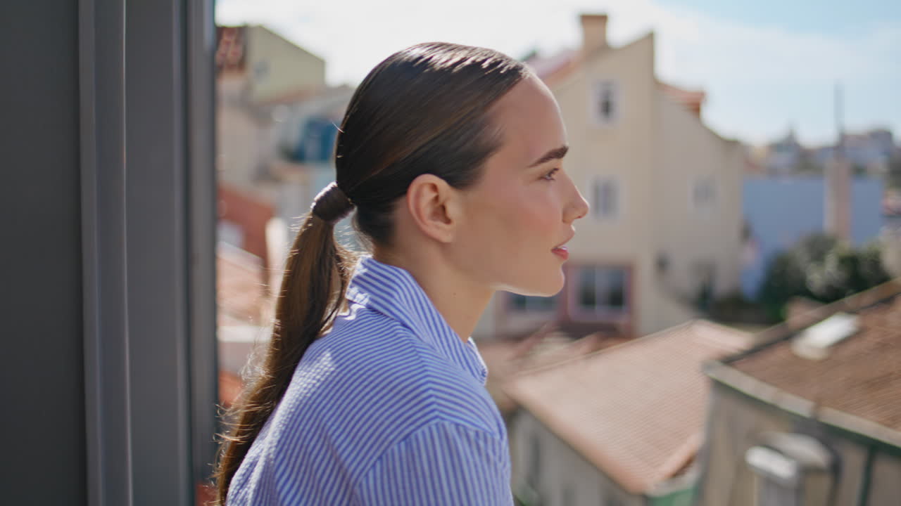 Happy lady enjoying wind sunshine balcony side portrait. Woman looking cityscape