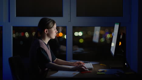 young good looking caucasian woman typing and working on the laptop computer as freelancer while sitting at home in the cozy dark living room with a cat. at night. stay home