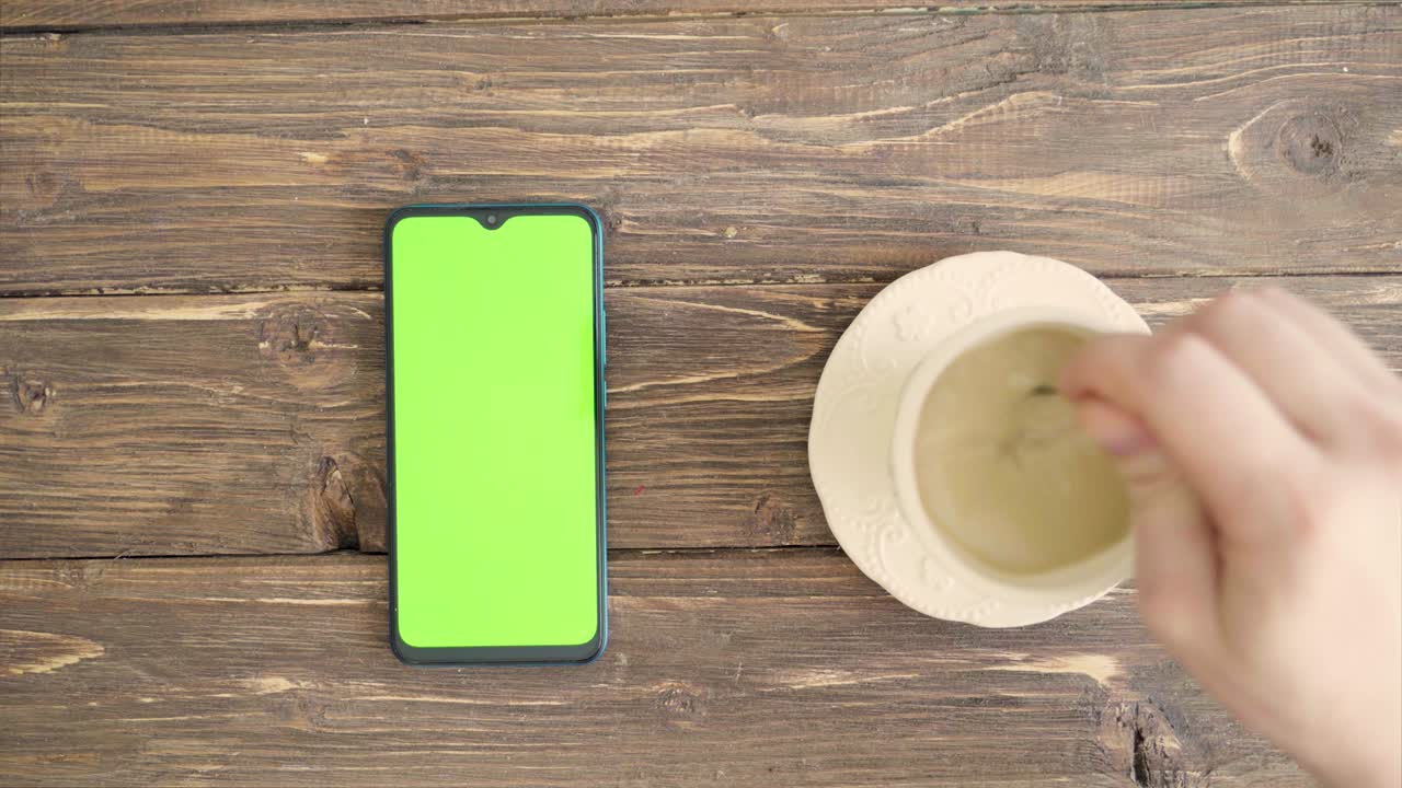 con taza de té y teléfono inteligente con llave de croma en la mesa y manos masculinas. vista de adobe