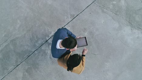 imágenes aéreas de drones: mujer de negocios y hombre de negocios usando un dispositivo de computadora tablet, realizando transacciones comerciales, haciendo un trato.