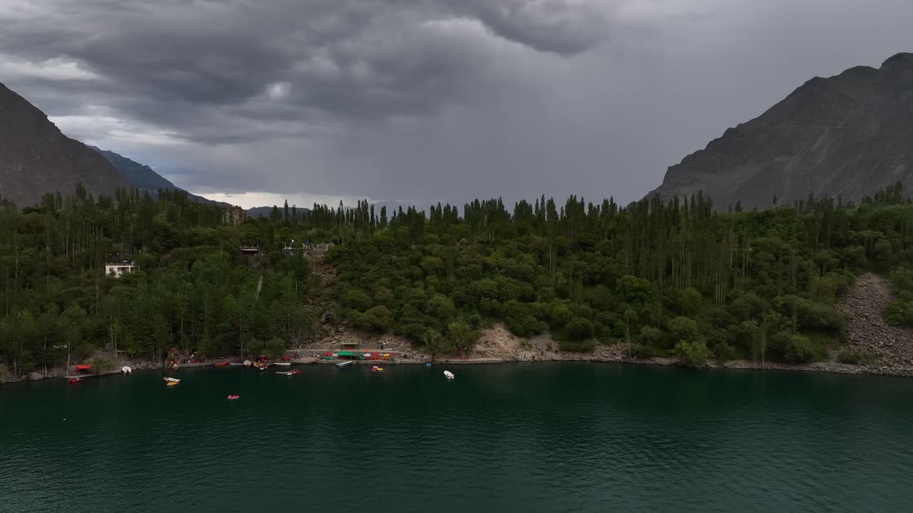 Riprese aeree con drone sopra il Lago Superiore di Kachura, Skardu, con acqua blu profondo e alberi verdi e rigogliosi sulla riva.