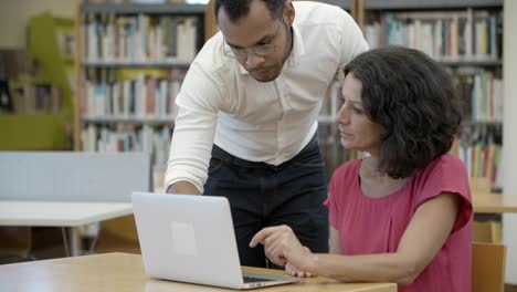 focused students working with laptop at library