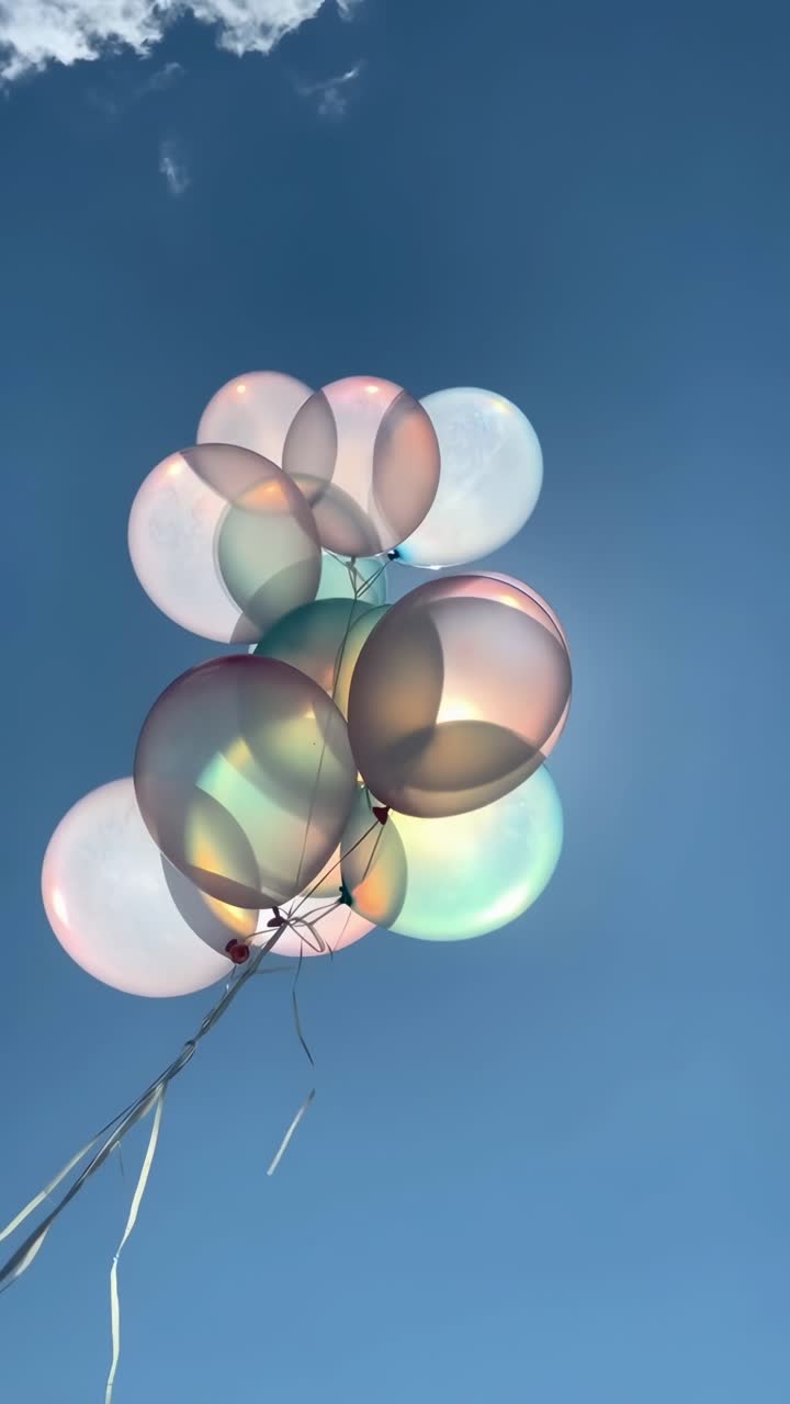 Palloncini iridescenti che fluttuano contro il cielo blu con la luce del sole
