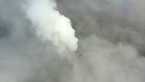 smoke from a power station chimney rising from a low, creeping fog. drone view