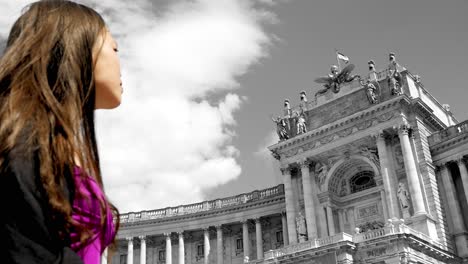 woman in selective color stands before the historical nationalbibliothek in vienna, with clouds overhead, close-up