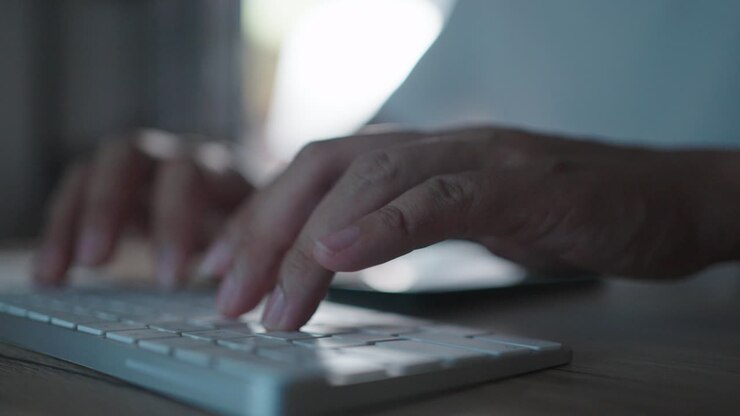 close up hands working overtime typing research laptop office desk at night