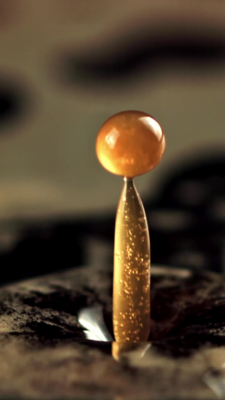 Gota de Líquido Dourado Cria um Salpico em Coroa e Recua em Câmera Lenta