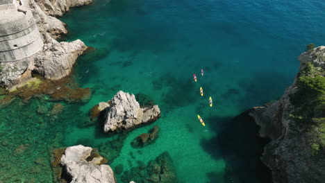 people kayaking in clear blue water in dubrovnik, croatia