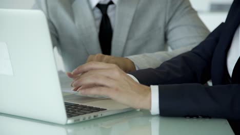 Cropped-shot-of-colleagues-using-laptop-at-workplace