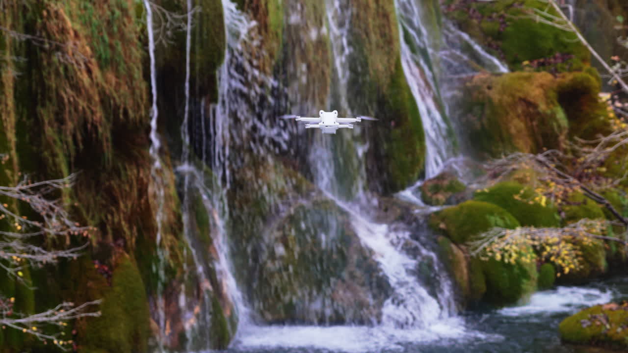 Aerial drone view of a mini drone hovering in front of lush moss covered waterfalls inside Plitvice Lakes National Park