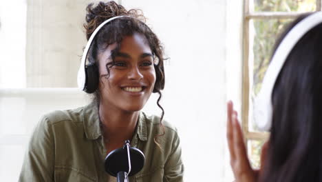 young woman wearing headphones recording podcast, engaging in lively conversation, at home