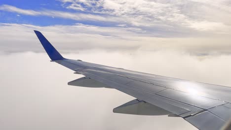 Static-shot-of-Airplane-Window-View-showing-shining-wing-and-clouds-during-landing-approach