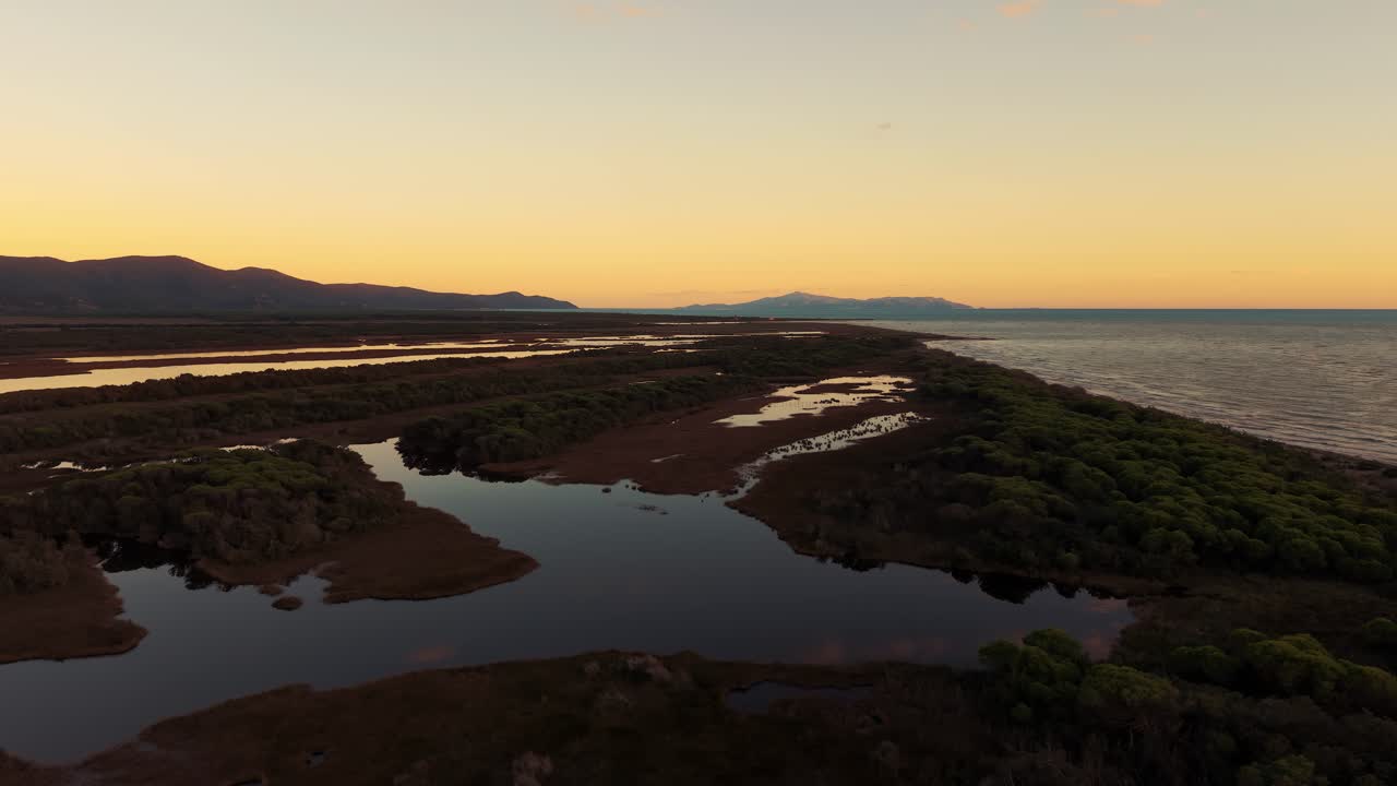 Riflessi sereni delle nuvole del tramonto nell'acqua della laguna sulla costa del Parco della Maremma. Toscana vista dall'alto