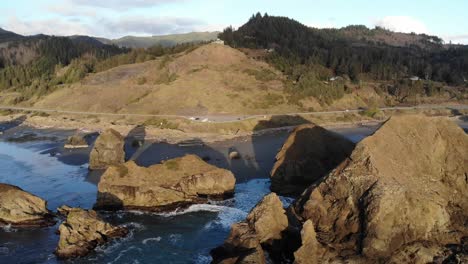 drone flies toward sea stacks and beach as sun goes down