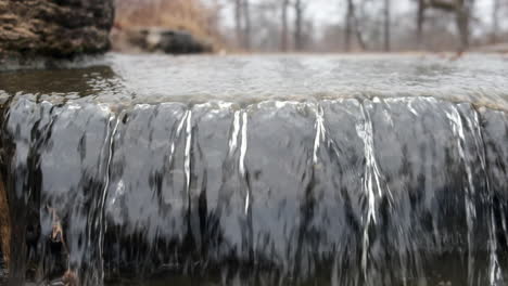 close up front view of a small waterfall rushing over a ledge in a river