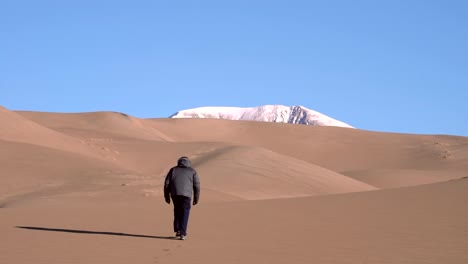 man walking on sand dunes in slow motion