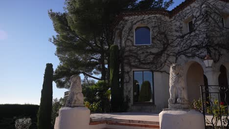 house with ivy growing in the walls and stone lions on the entrance in cannes france, tilt up shot