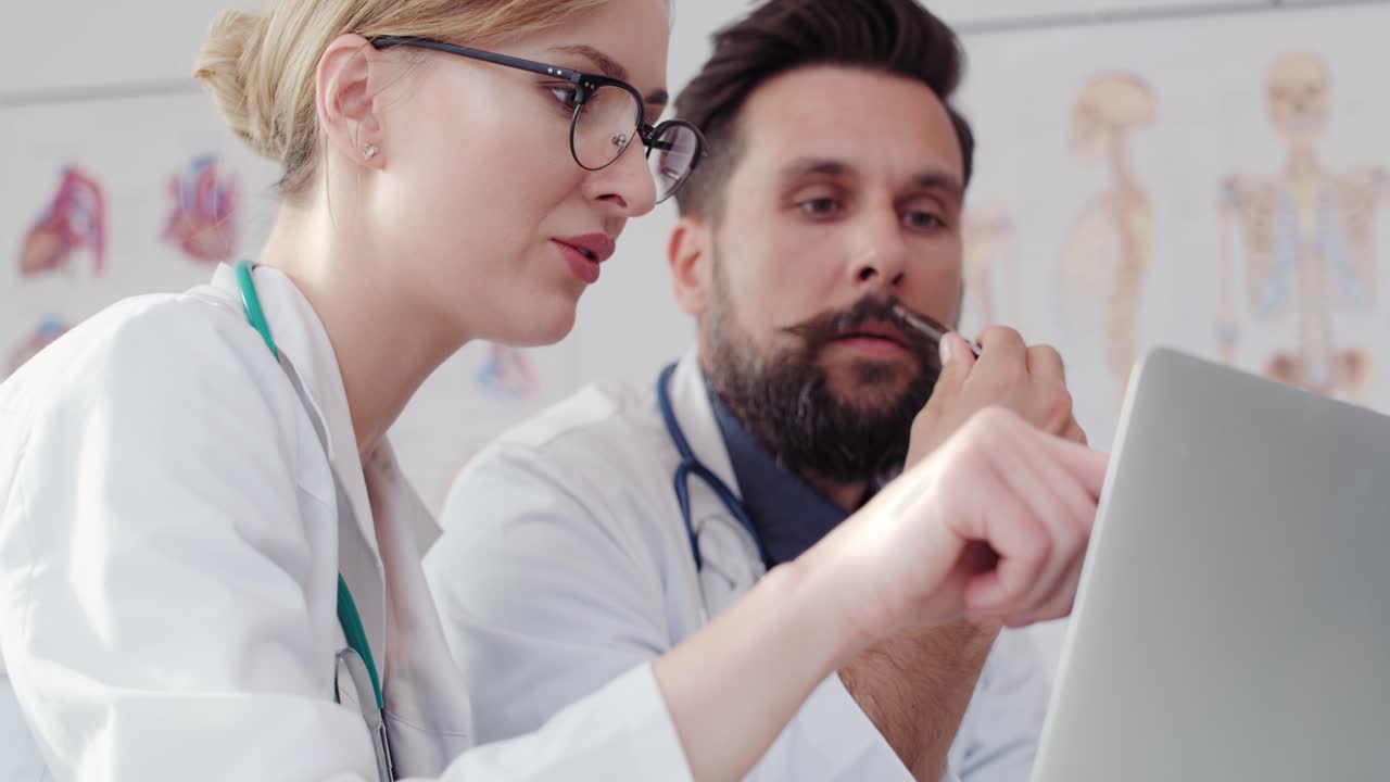 programas de video de mano de dos médicos ocupados mirando la computadora portátil