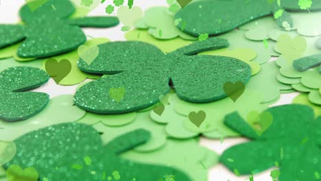 animation of st patrick's day shamrock and green hearts on white background