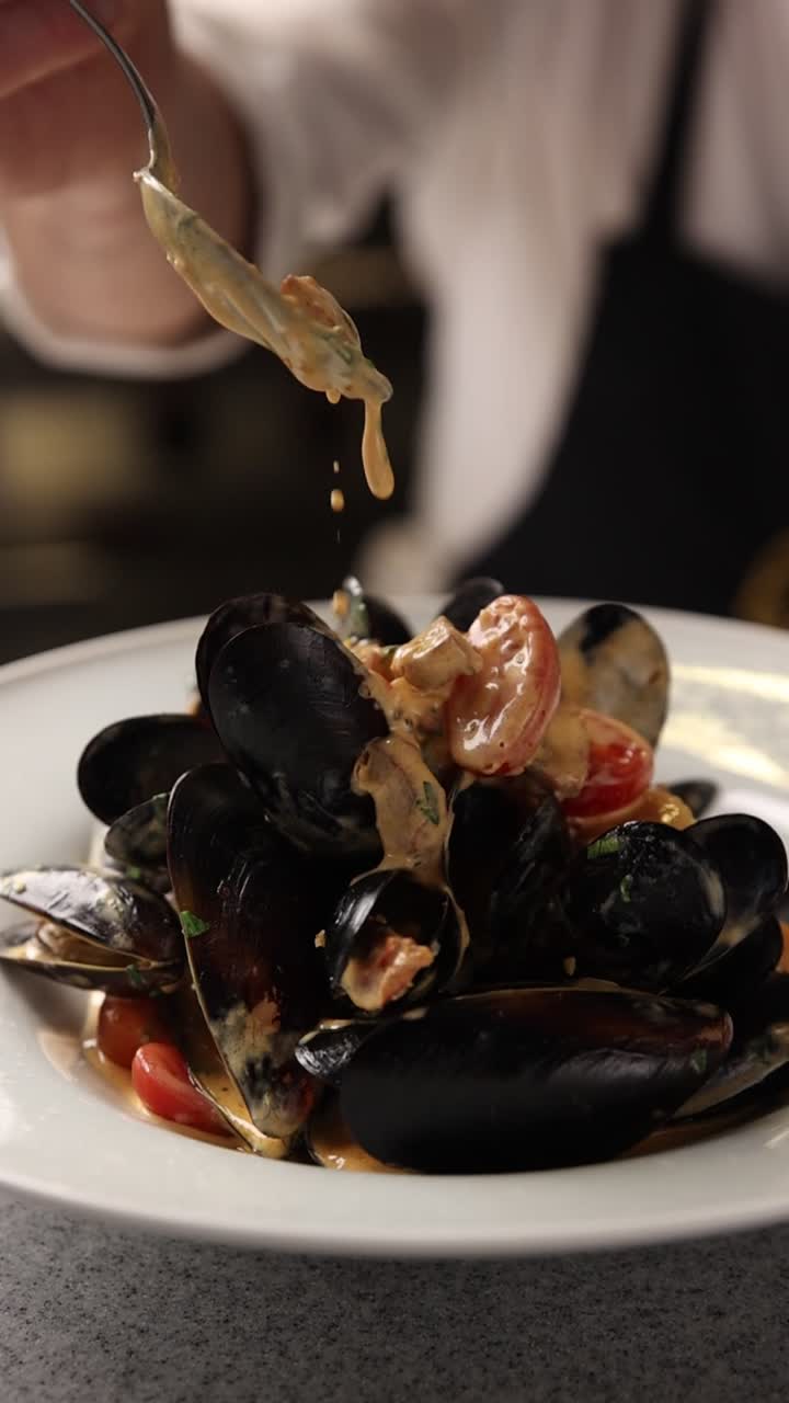Chef che versa salsa cremosa su un piatto di cozze