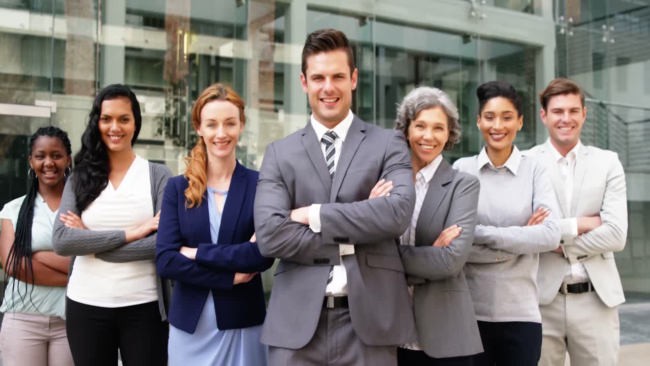 personas de negocios sonrientes de pie con los brazos cruzados en el edificio de oficinas
