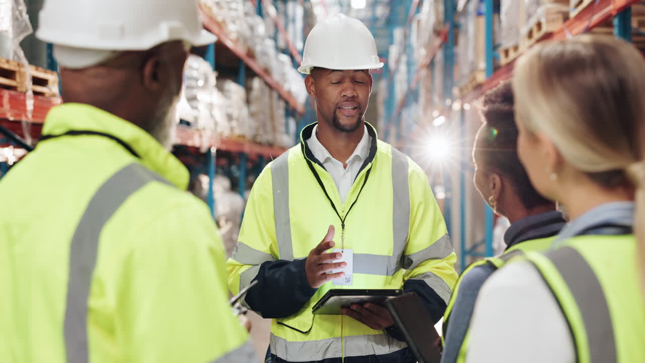 los trabajadores del almacén con chalecos de seguridad y cascos tienen una reunión en un almacén.
