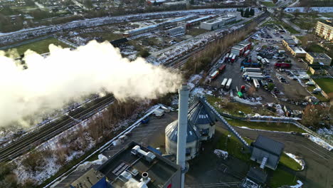 Industrielle-Schornsteine,-Die-Bei-Sonnenuntergang-Rauch-über-Einem-Vorstadtgebiet-Ausstoßen