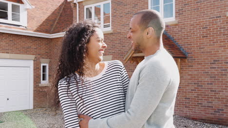 Portrait-Of-Couple-Holding-Keys-Standing-Outside-New-Home-On-Moving-Day